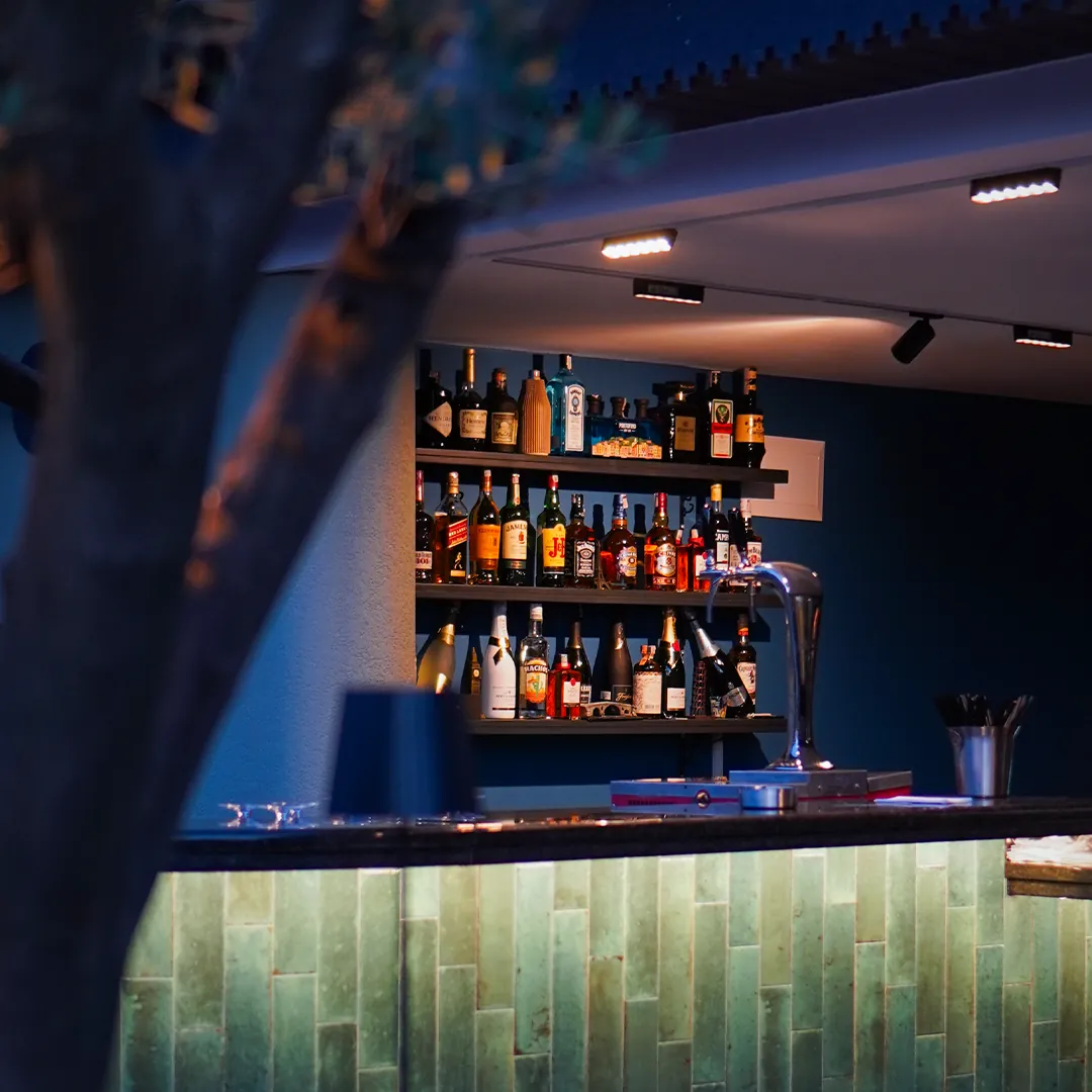 The bar with backlit shelves and green tiled counter
