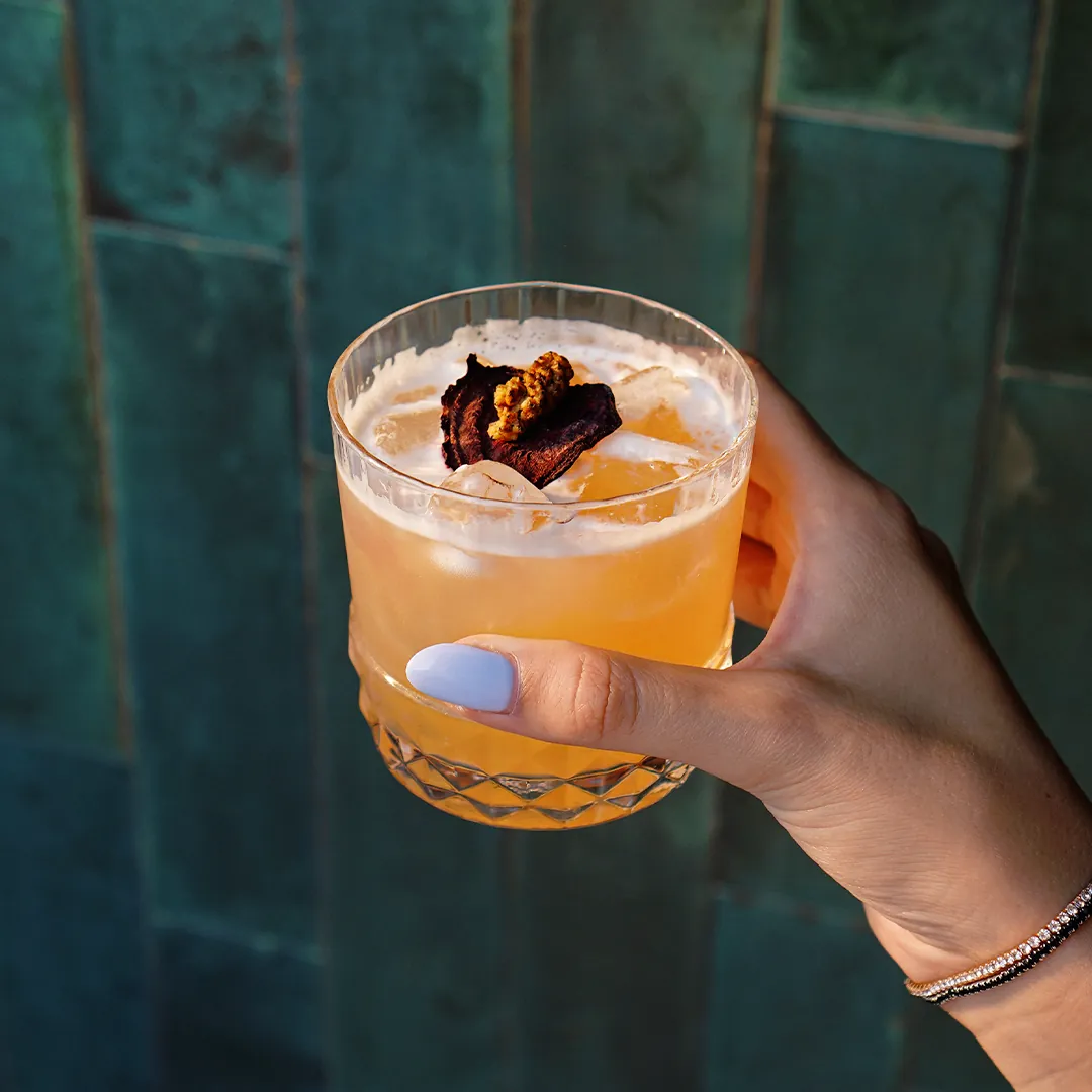 Spiced cocktail in a crystal glass against green tiles