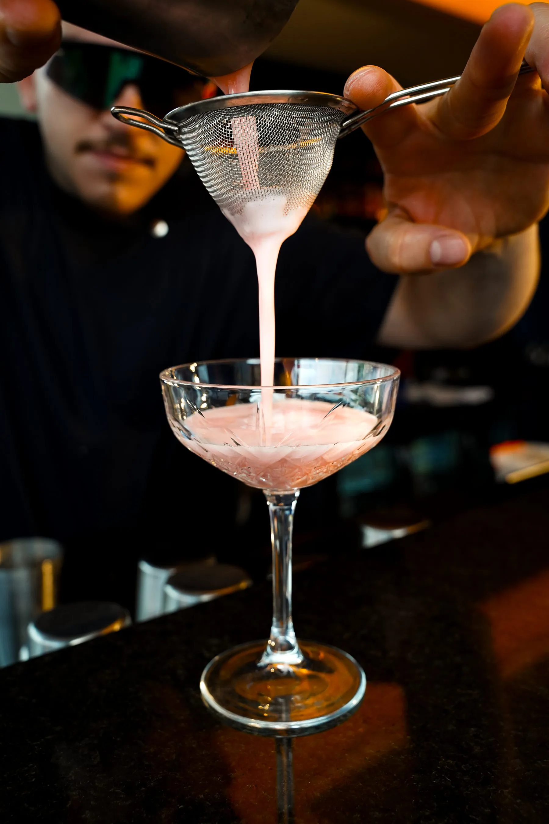 Straining a freshly shaken cocktail into a coupe